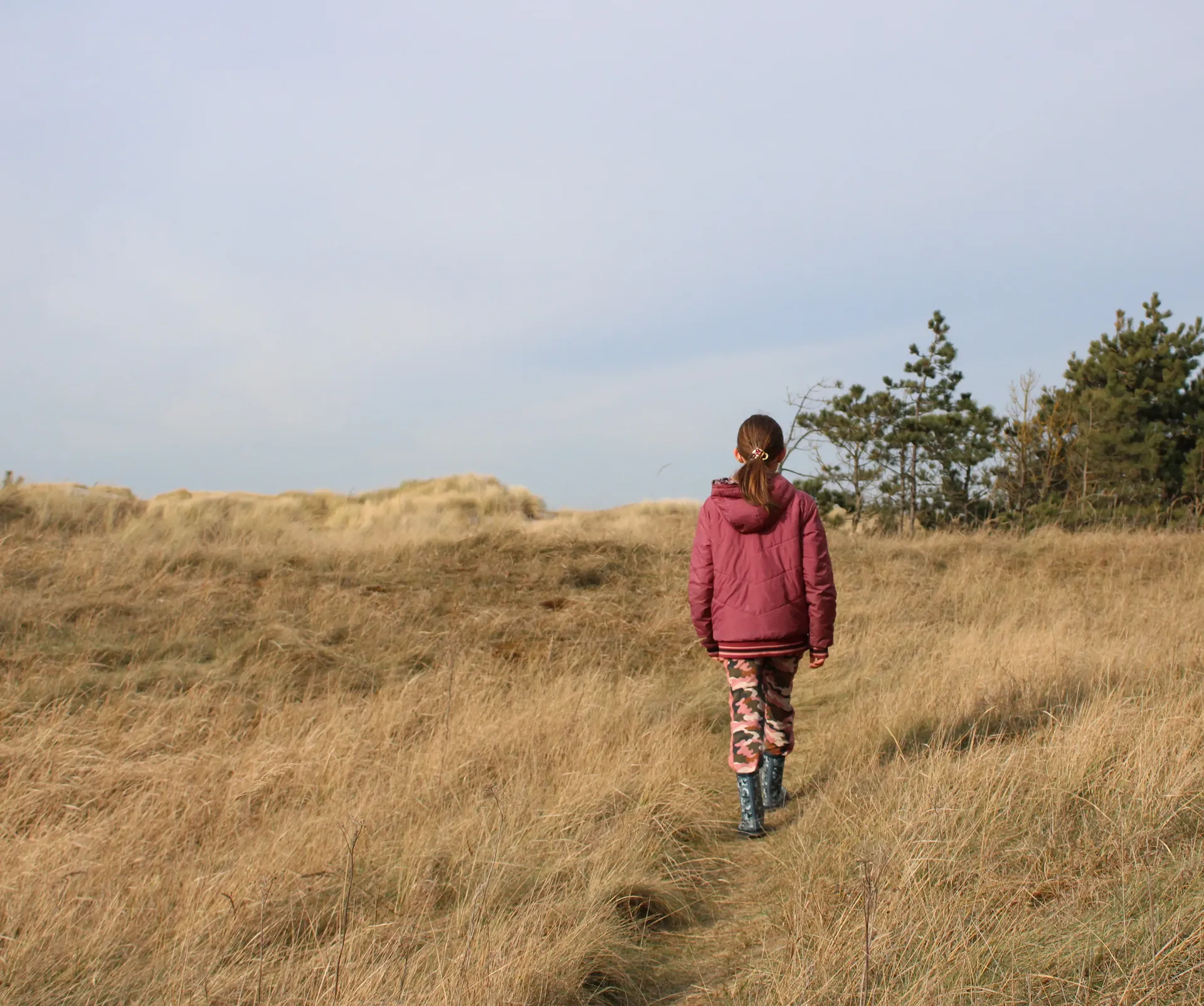 kind wandelt zelfverzekerd door duinen tijdens een wandeling