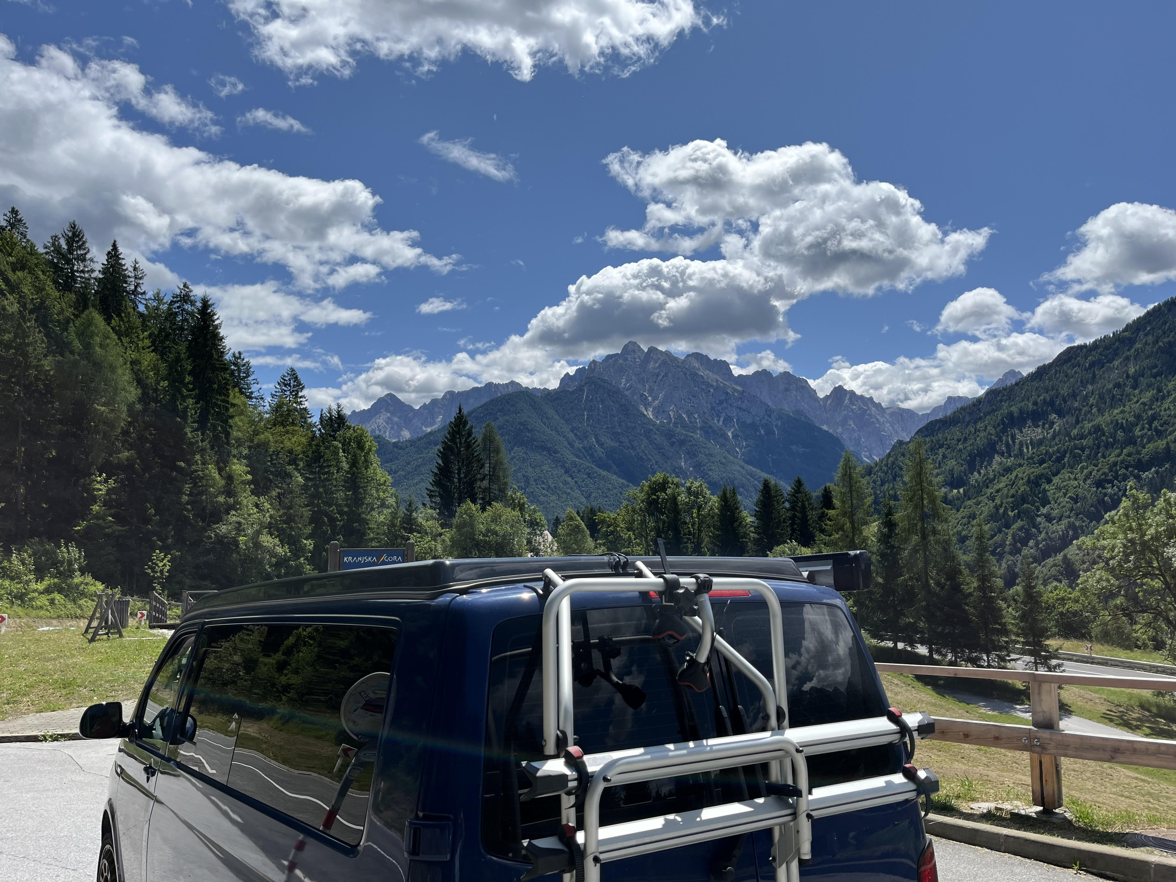 VW camper parked on the side of a mountain road with view over valley